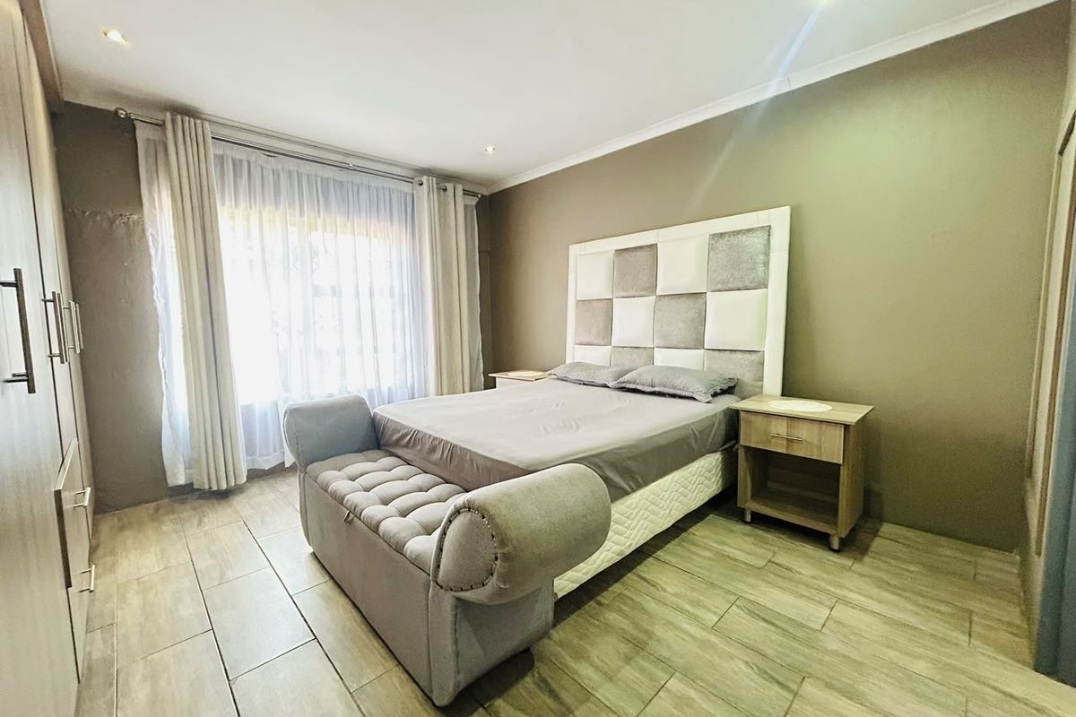 A well-maintained bedroom featuring tiled flooring, built-in cupboards, and recessed downlighting, offering a neutral and functional living space.