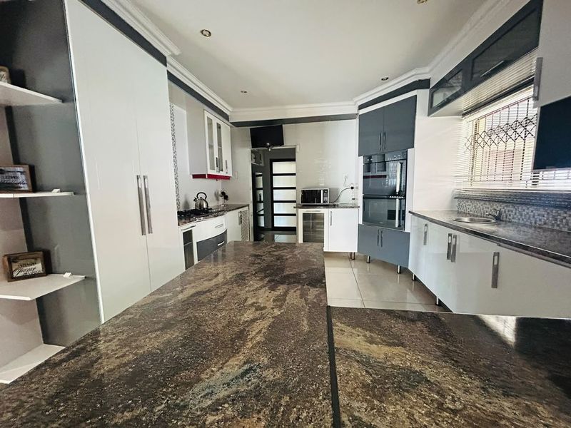 Modern kitchen featuring granite countertops, built-in oven and microwave, ample cabinetry, and tiled flooring, offering a functional and well-maintained cooking space.