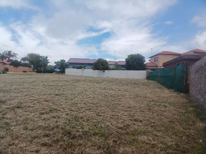 A vacant residential plot featuring a level grassed area enclosed by perimeter walls and boundary fencing.