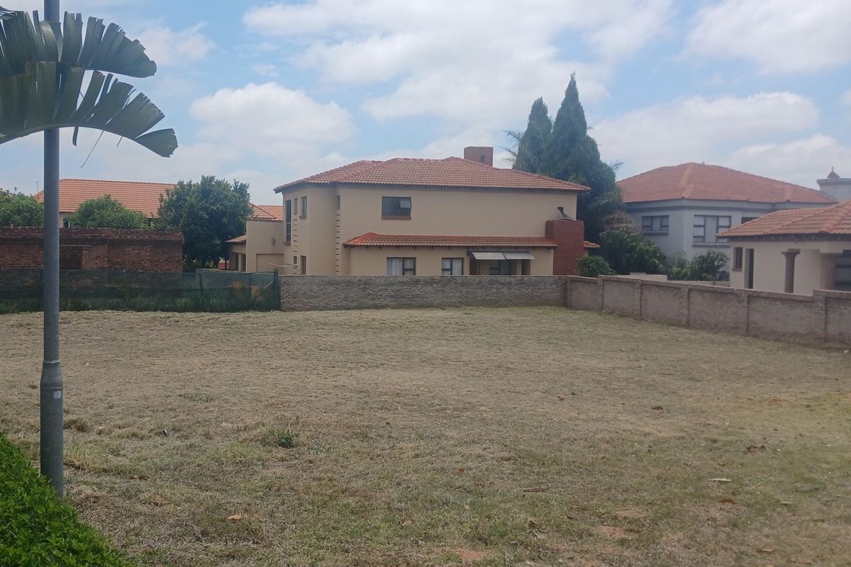 A vacant residential plot featuring a perimeter brick wall and established surrounding neighborhood views.