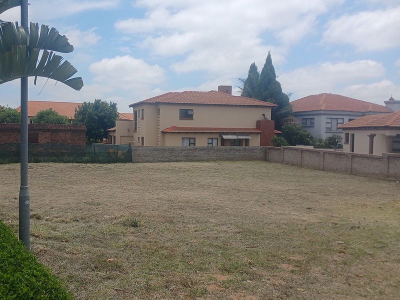 A vacant residential plot featuring a perimeter brick wall and established surrounding neighborhood views.