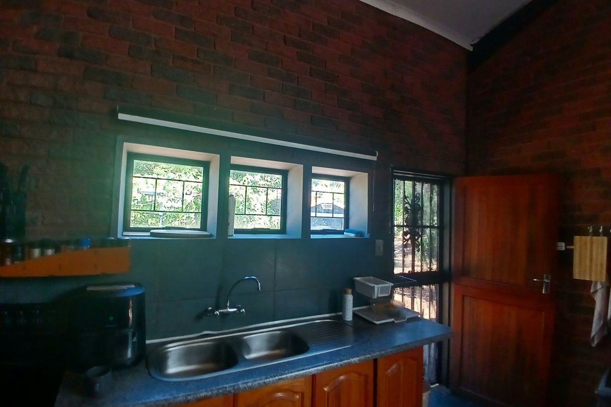 Kitchen area featuring exposed brick walls, wooden cabinetry, laminate countertops, and a double bowl stainless steel sink with a mixer tap.