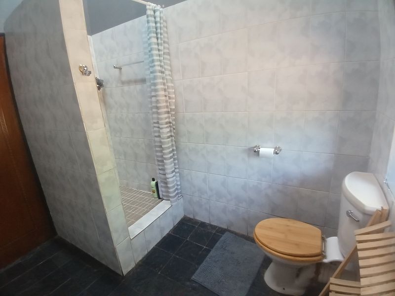 A functional bathroom featuring a walk-in shower with tiled walls and flooring, equipped with standard sanitary fixtures.