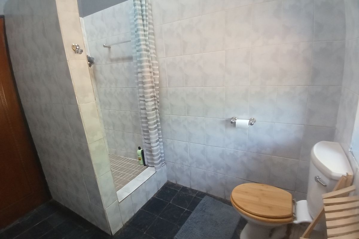 A functional bathroom featuring a walk-in shower with tiled walls and flooring, equipped with standard sanitary fixtures.
