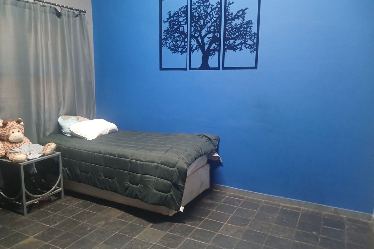 A bedroom featuring dark tiled flooring and a bold blue accent wall.