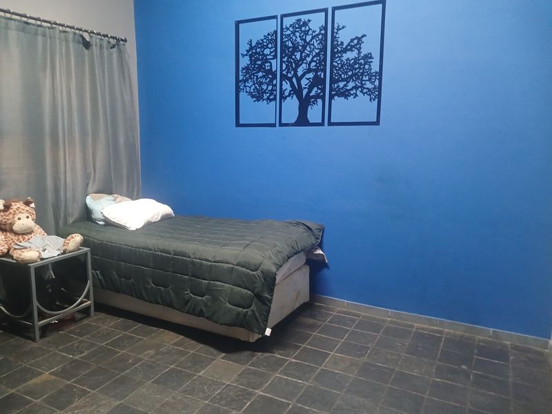 A bedroom featuring dark tiled flooring and a bold blue accent wall.