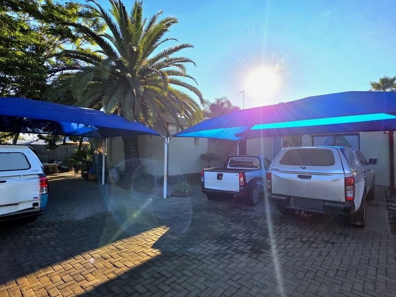Exterior view of the property featuring a paved driveway and multiple shade cloth carports providing covered parking space.