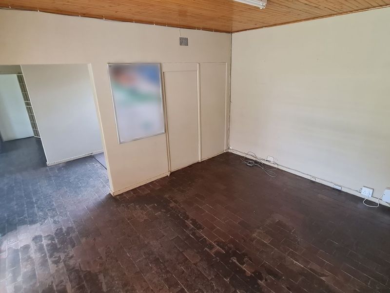 An empty office space featuring timber ceiling panels and dark brick flooring, offering a blank canvas for professional workspace customization.