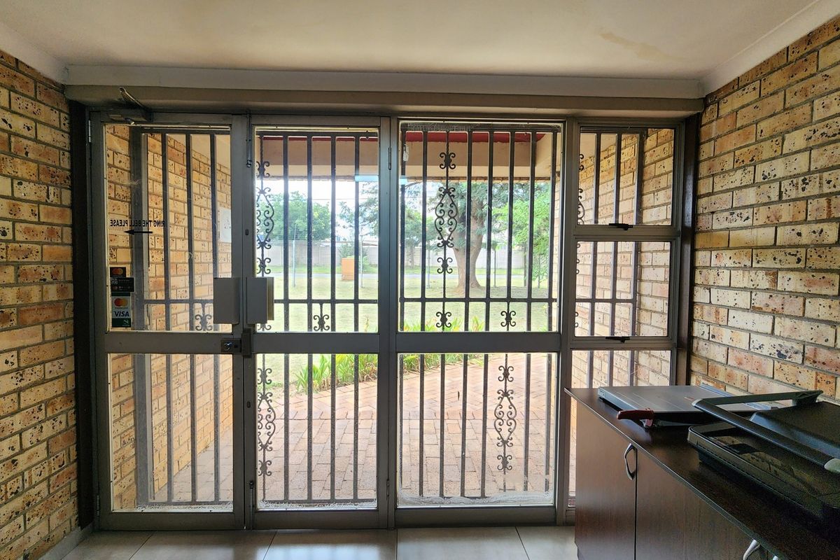 Entrance area featuring exposed brick walls, tiled flooring, and a secure aluminium-framed glass door leading to the exterior.