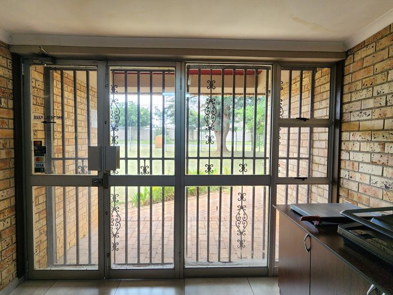 Entrance area featuring exposed brick walls, tiled flooring, and a secure aluminium-framed glass door leading to the exterior.
