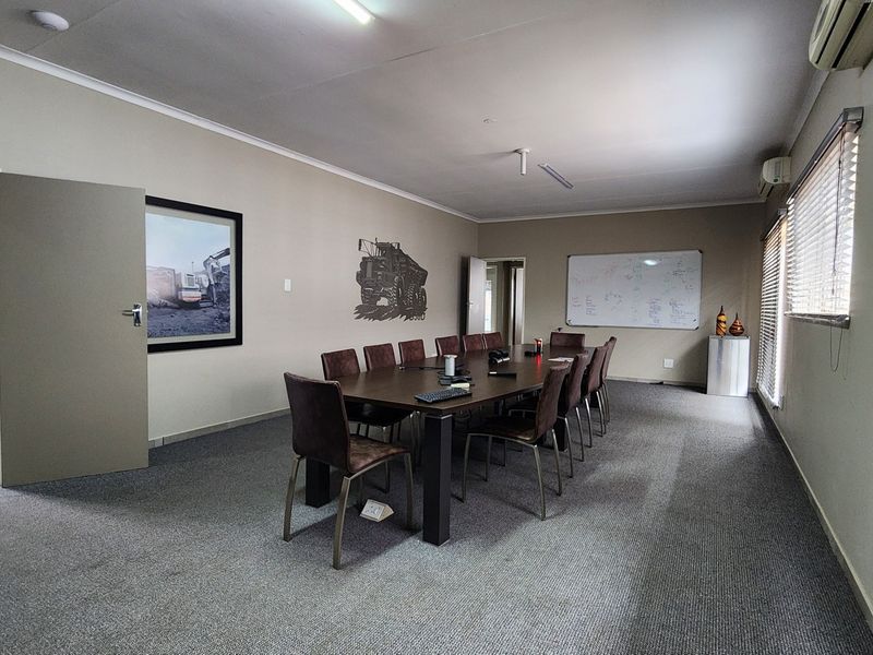 A functional commercial office or boardroom space featuring carpeted flooring, wall-mounted whiteboard, and integrated air conditioning units.