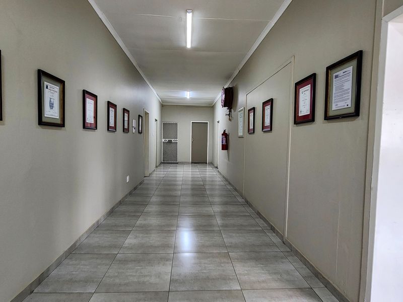 A clean, well-maintained commercial hallway featuring neutral wall tones, tiled flooring, and integrated fire safety equipment.