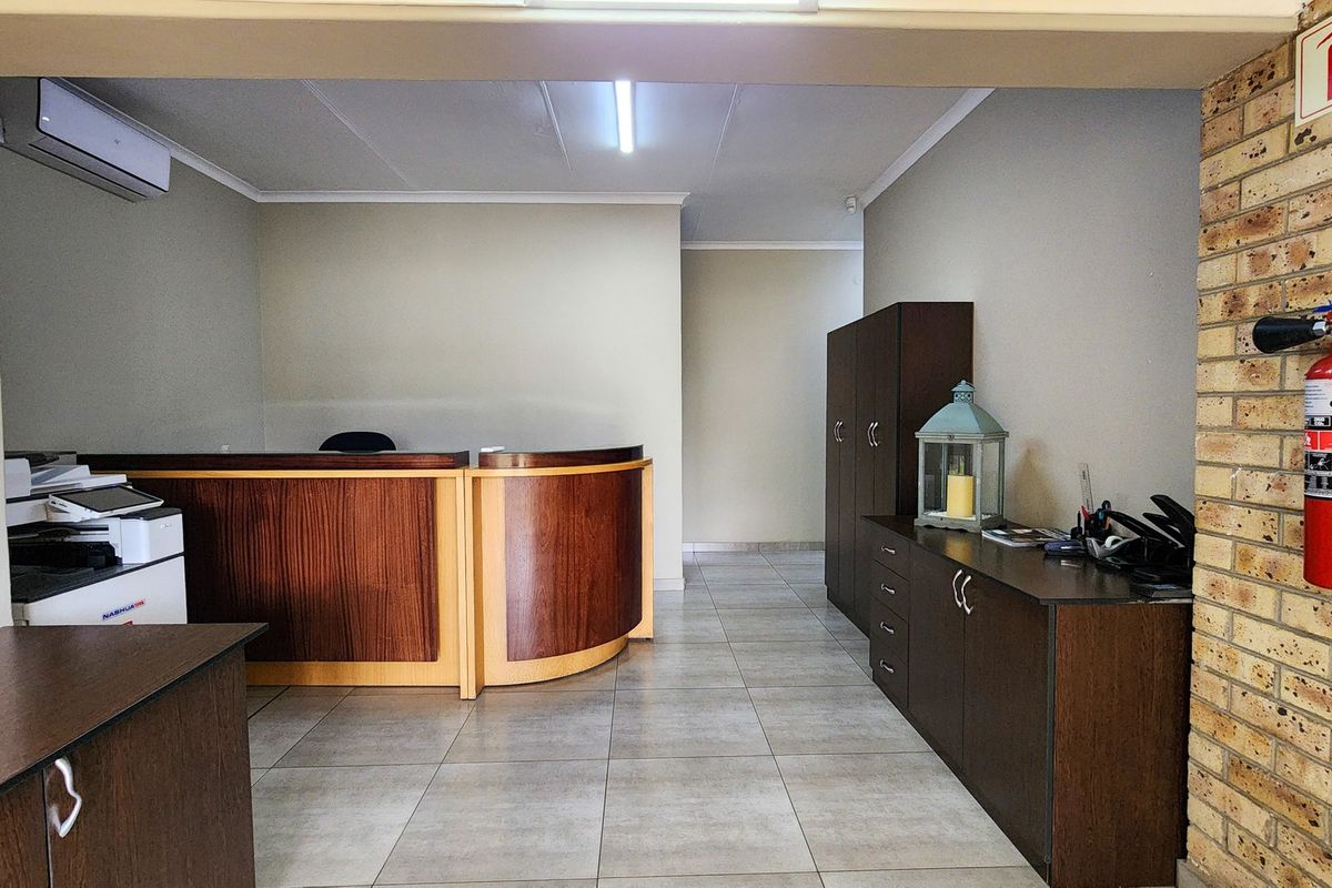 A professional commercial office space featuring a built-in reception desk, tiled flooring, exposed brick accents, and integrated air conditioning.