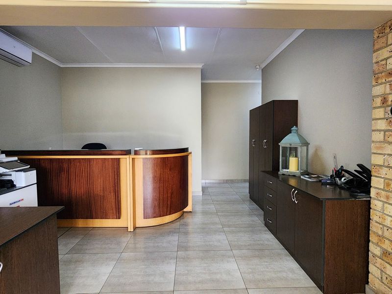 A professional commercial office space featuring a built-in reception desk, tiled flooring, exposed brick accents, and integrated air conditioning.