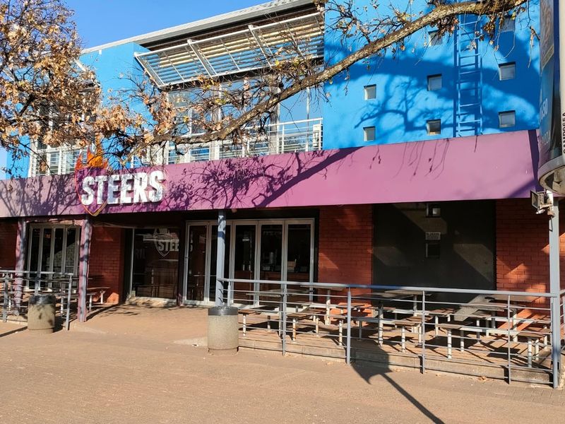 Front exterior view of a commercial office or retail building featuring a brick facade, glass storefront, and metal railing.