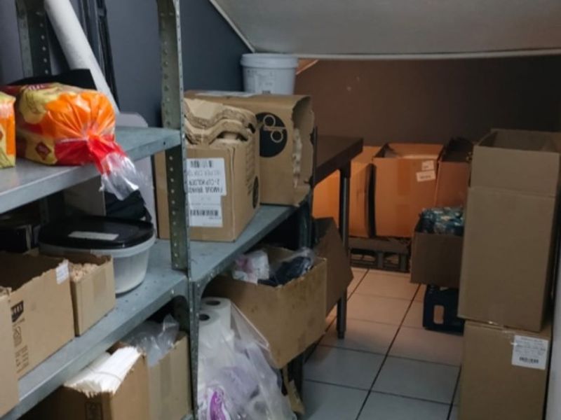 A functional utility or storage space featuring tiled flooring and a sloped ceiling, currently utilized for inventory storage.