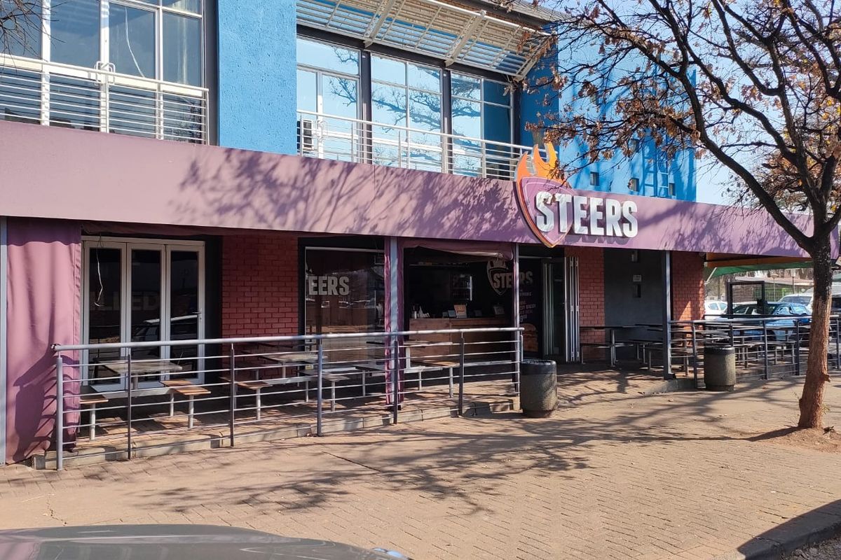 Front exterior view of a commercial office or retail space featuring a brick facade, metal railings, and a prominent storefront awning.