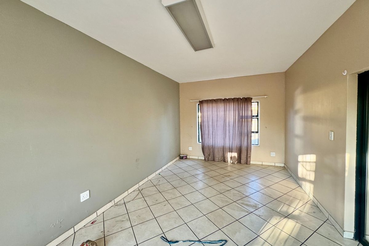 An empty living room featuring tiled flooring, neutral wall tones, and a central ceiling light fixture, ready for personalization.
