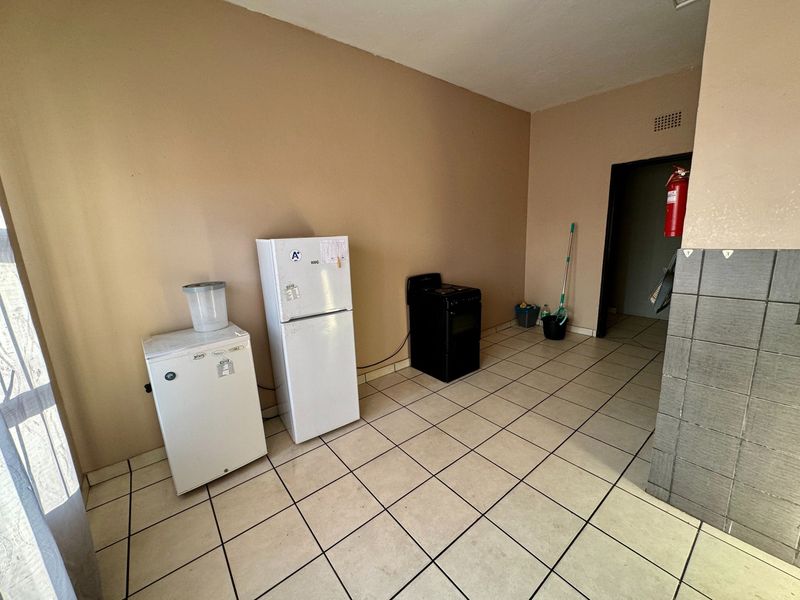 A basic kitchen area featuring tiled flooring and a fire extinguisher, currently lacking built-in cabinetry or countertops.