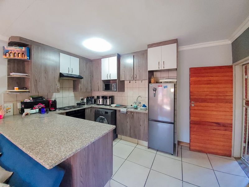 Functional kitchen featuring laminate cabinetry, granite countertops, built-in appliances, and tiled flooring, offering a practical layout for daily cooking and preparation.