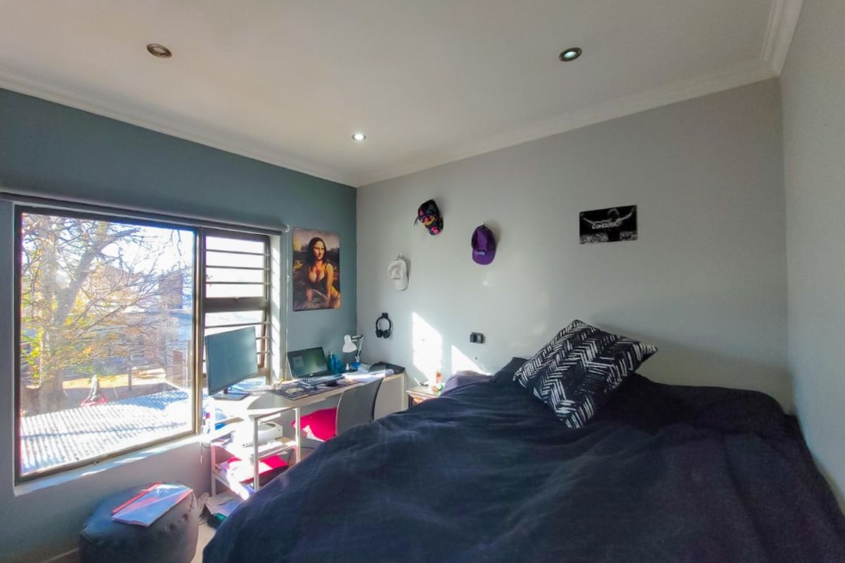 A functional bedroom featuring tiled flooring, recessed downlighting, and a large window providing natural light and exterior views.