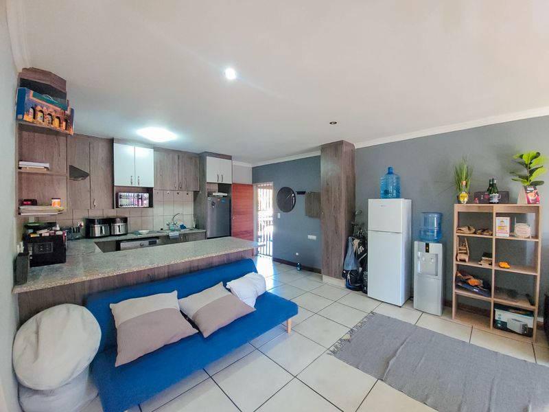 Open plan living area featuring a kitchen with granite countertops and built-in cabinetry, seamlessly flowing into a tiled living space.