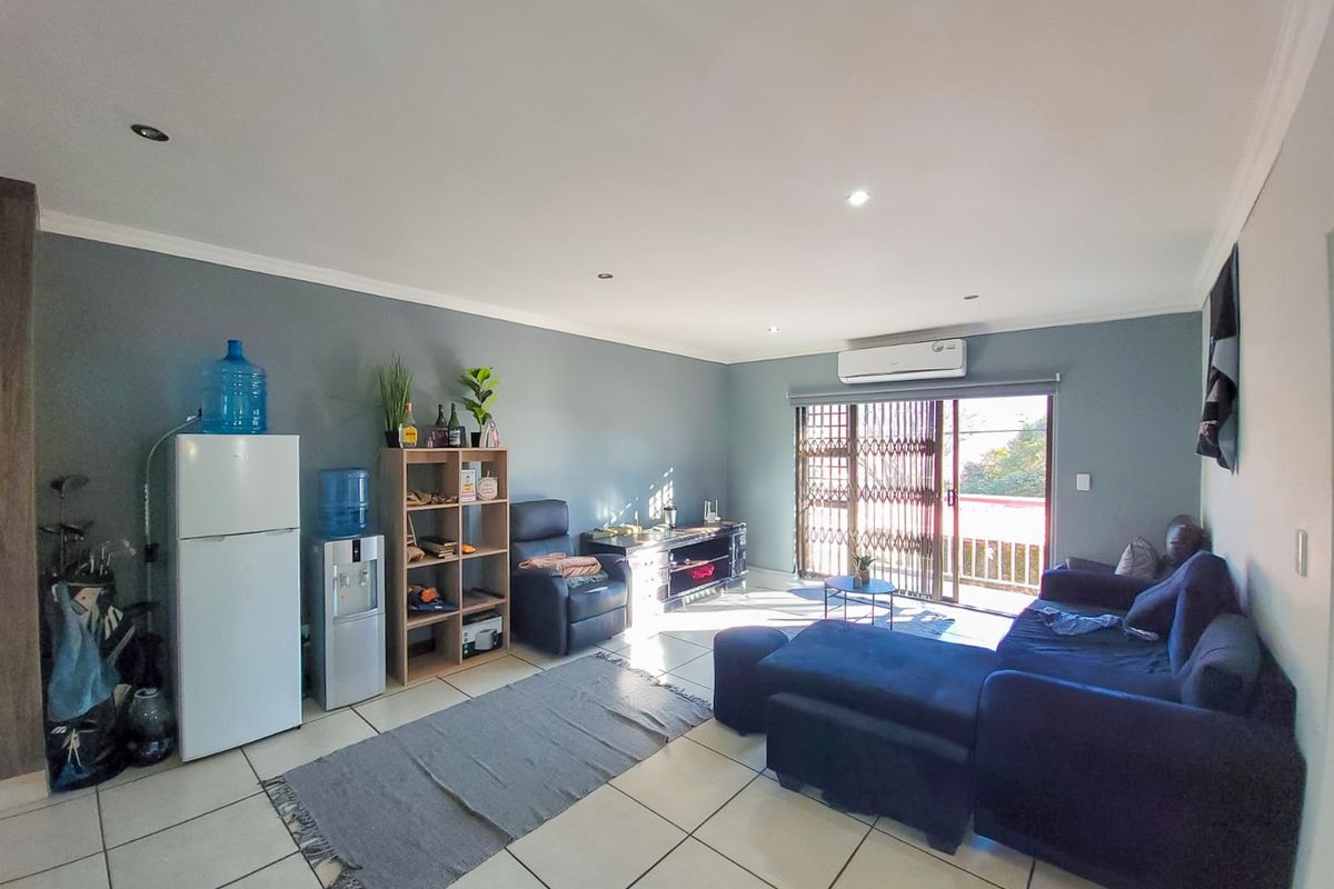 Spacious living room featuring tiled flooring, recessed lighting, and a split-system air conditioner, with direct access to an outdoor balcony through a sliding glass door.