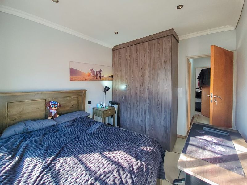 A well-maintained bedroom featuring a large built-in wardrobe, recessed ceiling lighting, and neutral wall finishes.