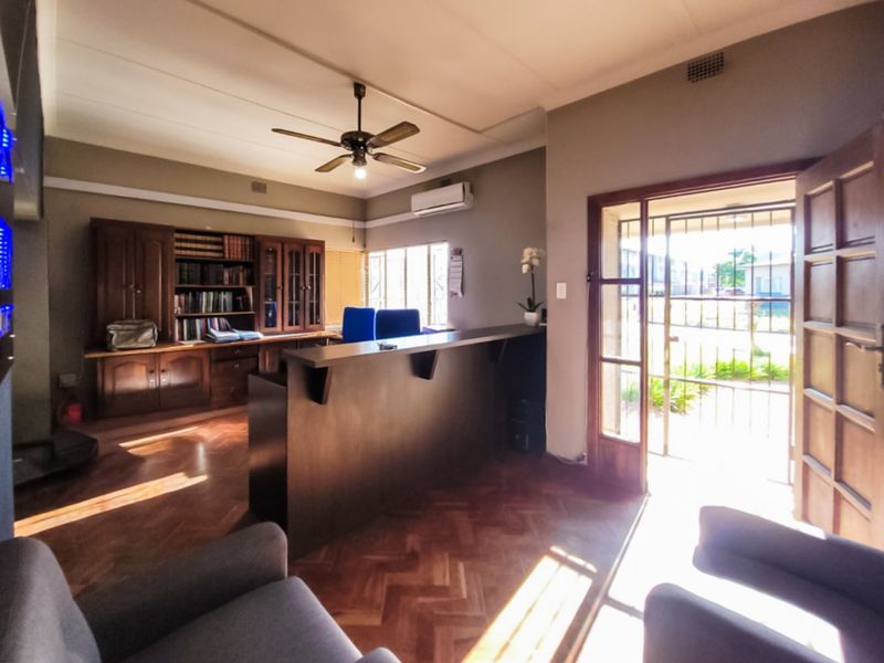 Professional office space featuring built-in cabinetry, a reception counter, parquet flooring, and direct access to the exterior via a security gate.