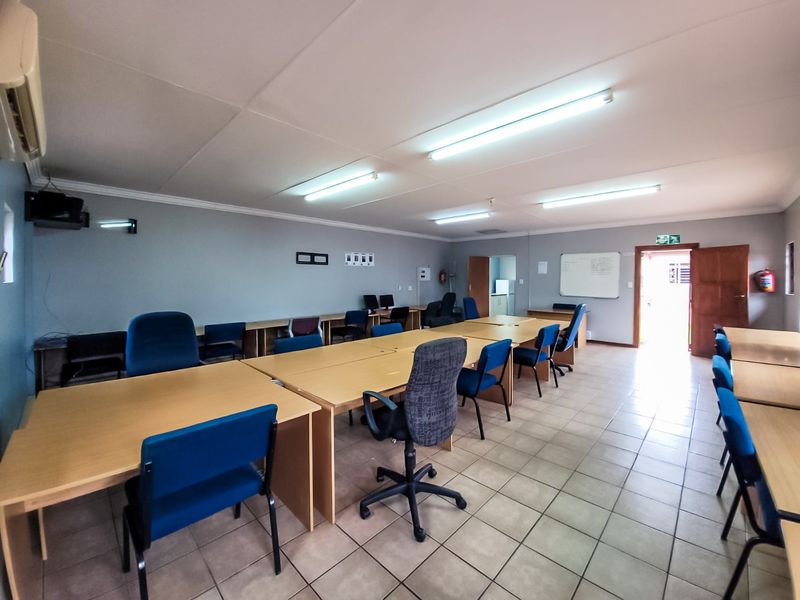 A functional commercial office space featuring ceramic tile flooring, fluorescent lighting, and an integrated air conditioning unit.
