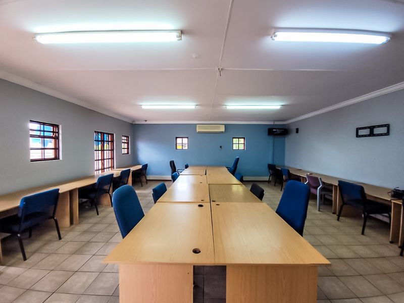 A functional commercial office space featuring tiled flooring, built-in desk configurations, and wall-mounted air conditioning, suitable for a collaborative work environment.