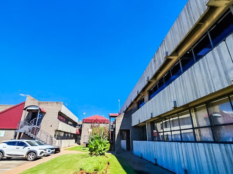 Exterior view of a commercial building complex featuring concrete facades, large windows, and a paved driveway area.