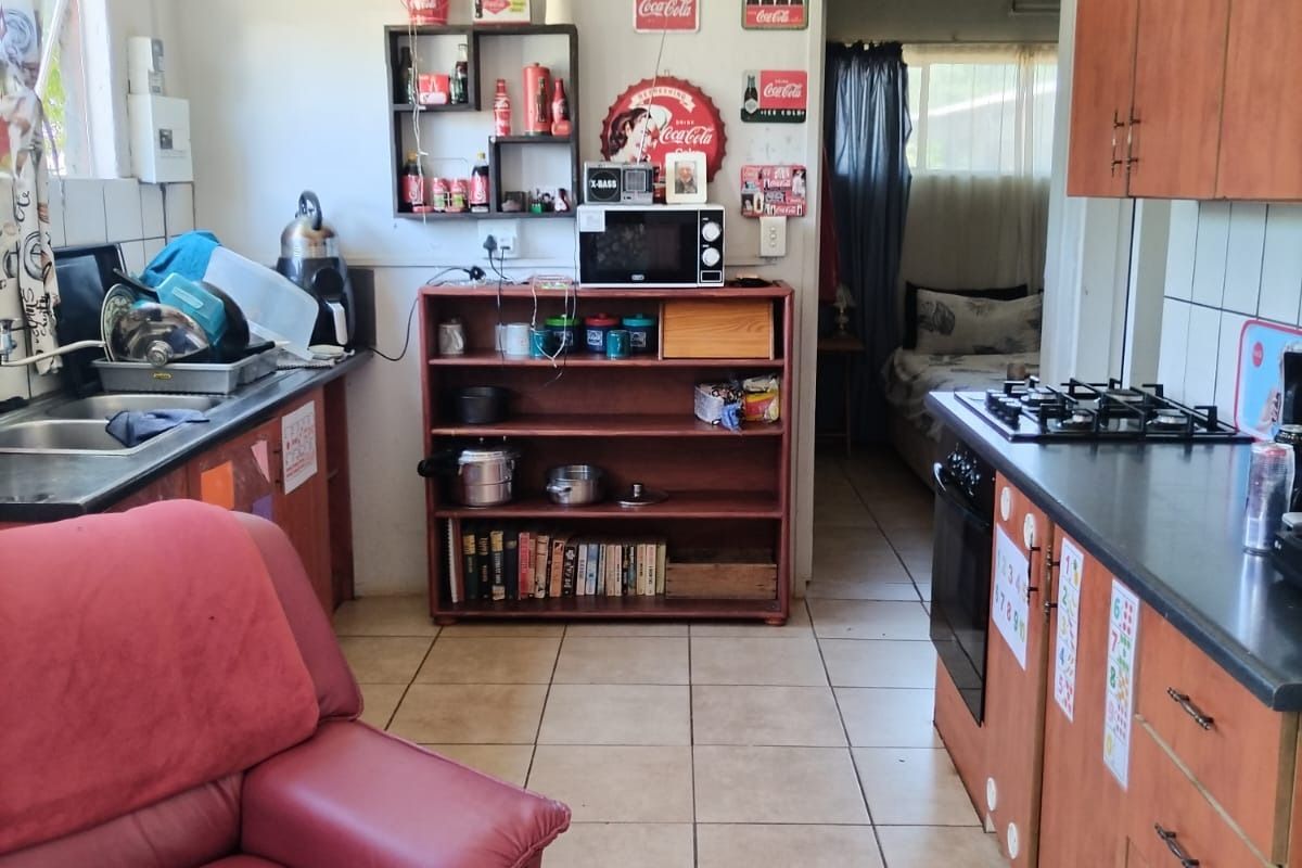 A functional kitchen featuring wooden cabinetry, laminate countertops, a gas hob, and an integrated oven, with tiled flooring and splashbacks throughout.