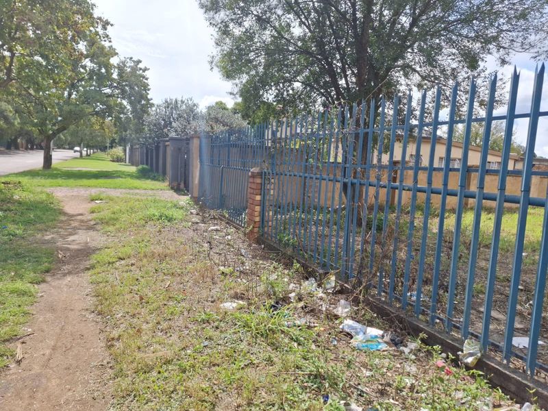 Street view of the property boundary featuring steel palisade fencing with brick pillars along the sidewalk.