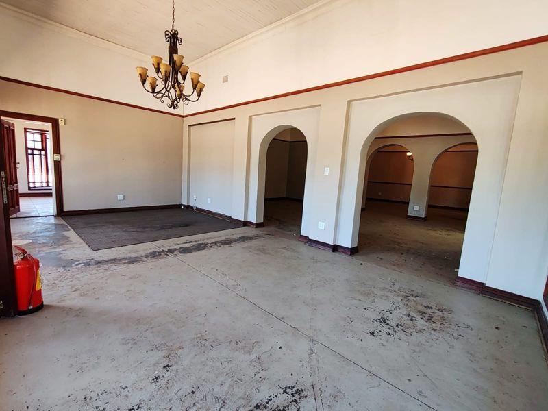 Spacious open-plan interior featuring distinctive arched doorways, high ceilings with a chandelier, and concrete flooring, offering a versatile layout for business use.