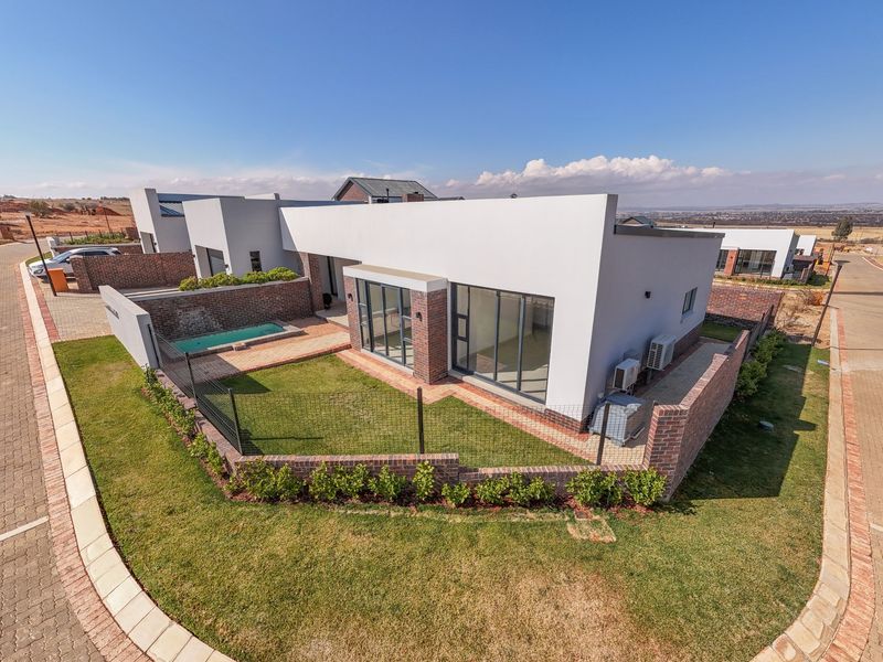 Aerial view of a modern residential property featuring a private garden, small swimming pool, paved patio area, and contemporary brick and plaster facade.