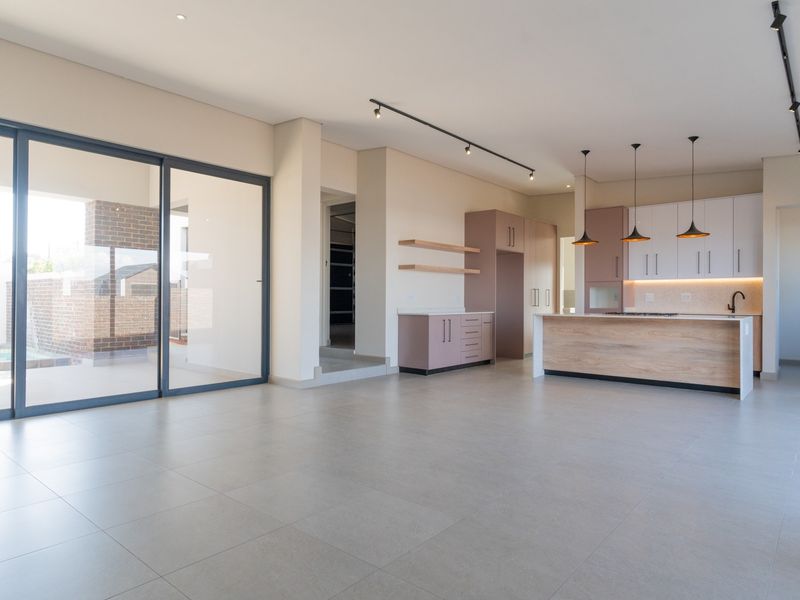 Spacious open-plan living and kitchen area featuring modern cabinetry, a central island, tiled floors, and large sliding doors leading to the outdoor patio.