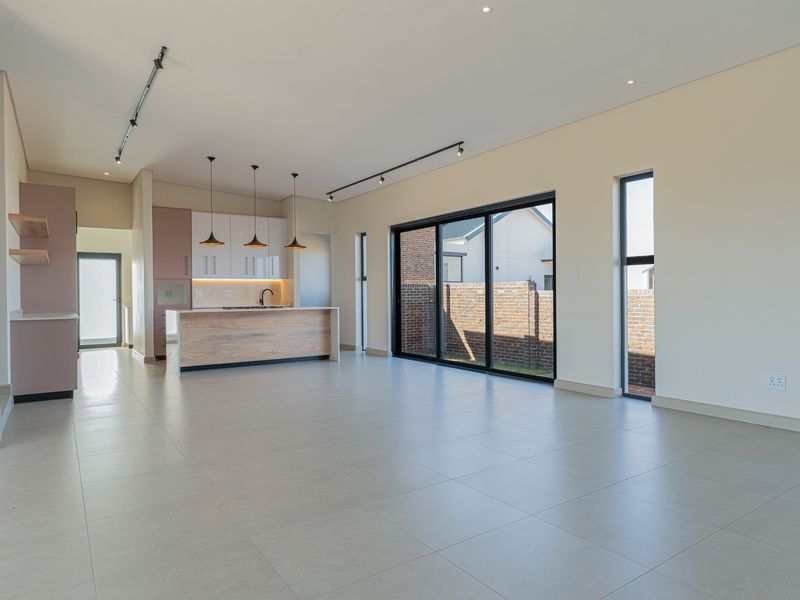 Spacious open-plan living area featuring a modern kitchen with island, sleek cabinetry, tiled floors, and large sliding doors leading to the exterior.