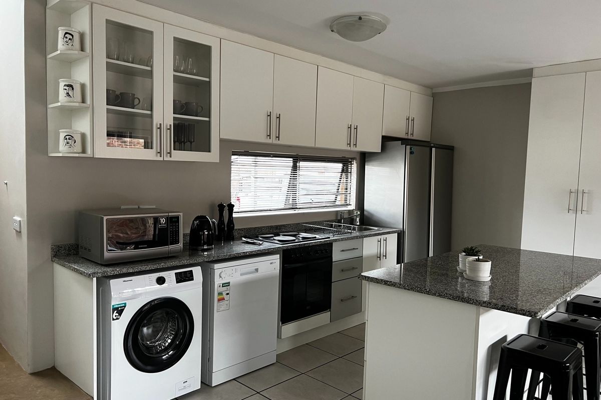 Modern kitchen featuring granite countertops, ample cabinetry, a central island, and integrated appliance spaces, finished with neutral tones and tiled flooring.