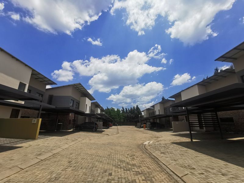 A view of the townhouse complex driveway featuring paved surfaces and covered carports for residents.