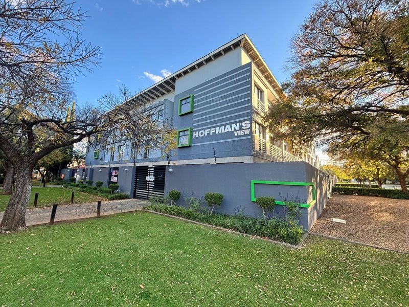 Exterior view of Hoffman's View apartment complex featuring modern facade, secure perimeter wall with electric fencing, and well-maintained garden area.