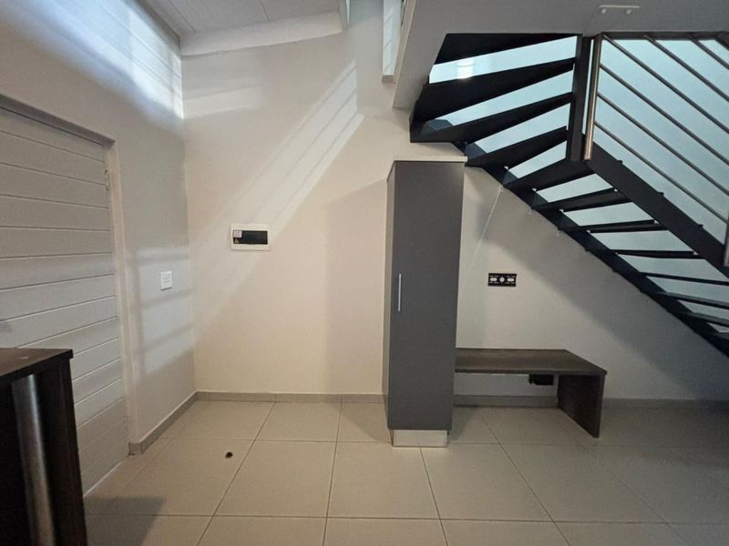 An entrance area featuring a modern staircase with a metal balustrade, tiled flooring, and a built-in storage unit.