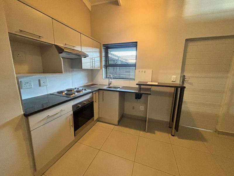 Modern kitchen featuring sleek cabinetry, built-in oven and hob, stainless steel sink, and a convenient breakfast bar area with tiled flooring.