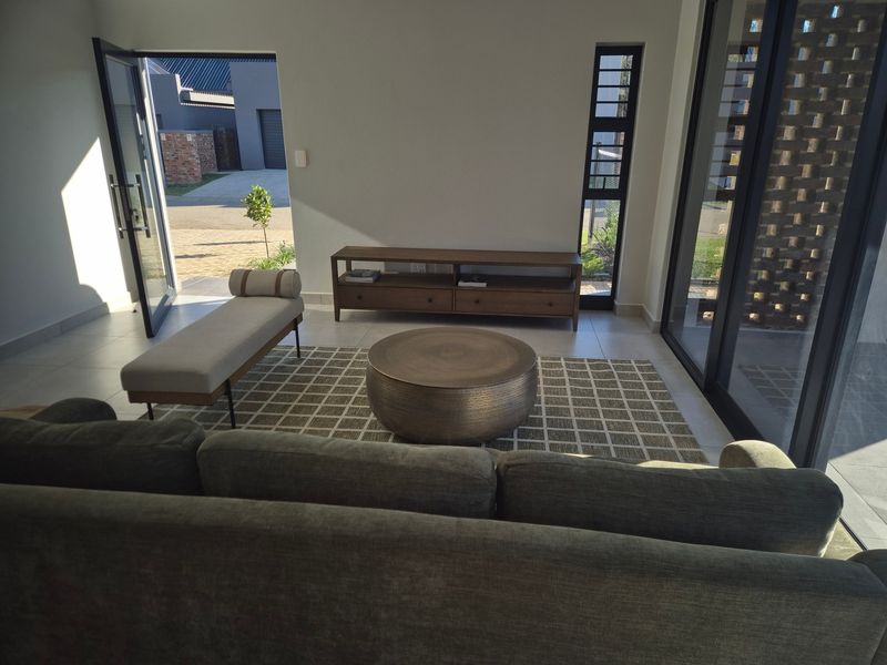 A bright and modern living room featuring large glass sliding doors that provide seamless access to the outdoor area and ample natural light.