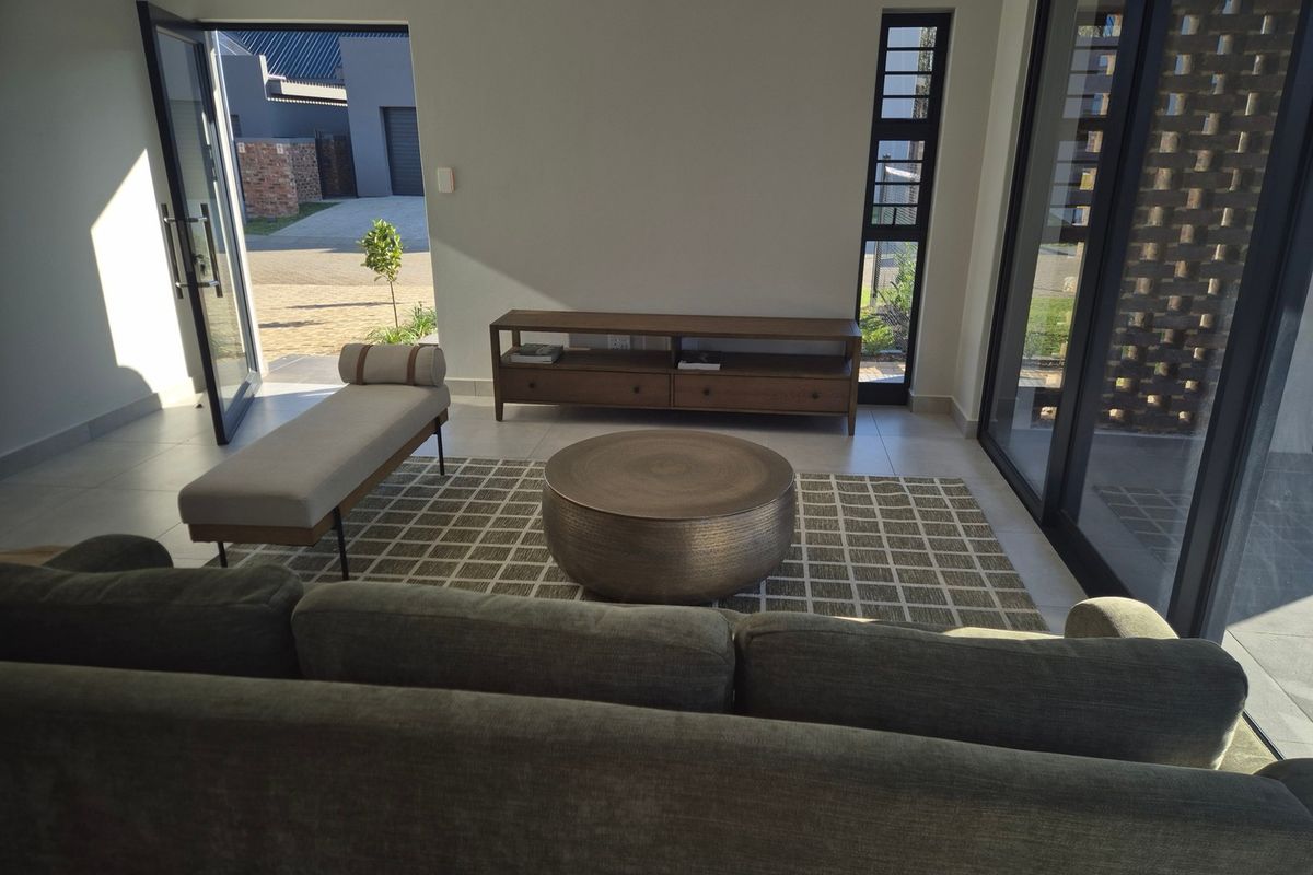 A bright and modern living room featuring large glass sliding doors that provide seamless access to the outdoor area and ample natural light.
