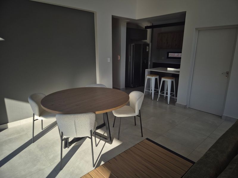 Open plan living and dining area featuring modern tiled flooring and a functional kitchen breakfast bar with built-in cabinetry.