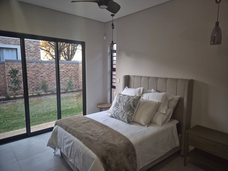 Modern bedroom featuring tiled flooring, ceiling fan, and large sliding glass doors providing direct access to the garden.