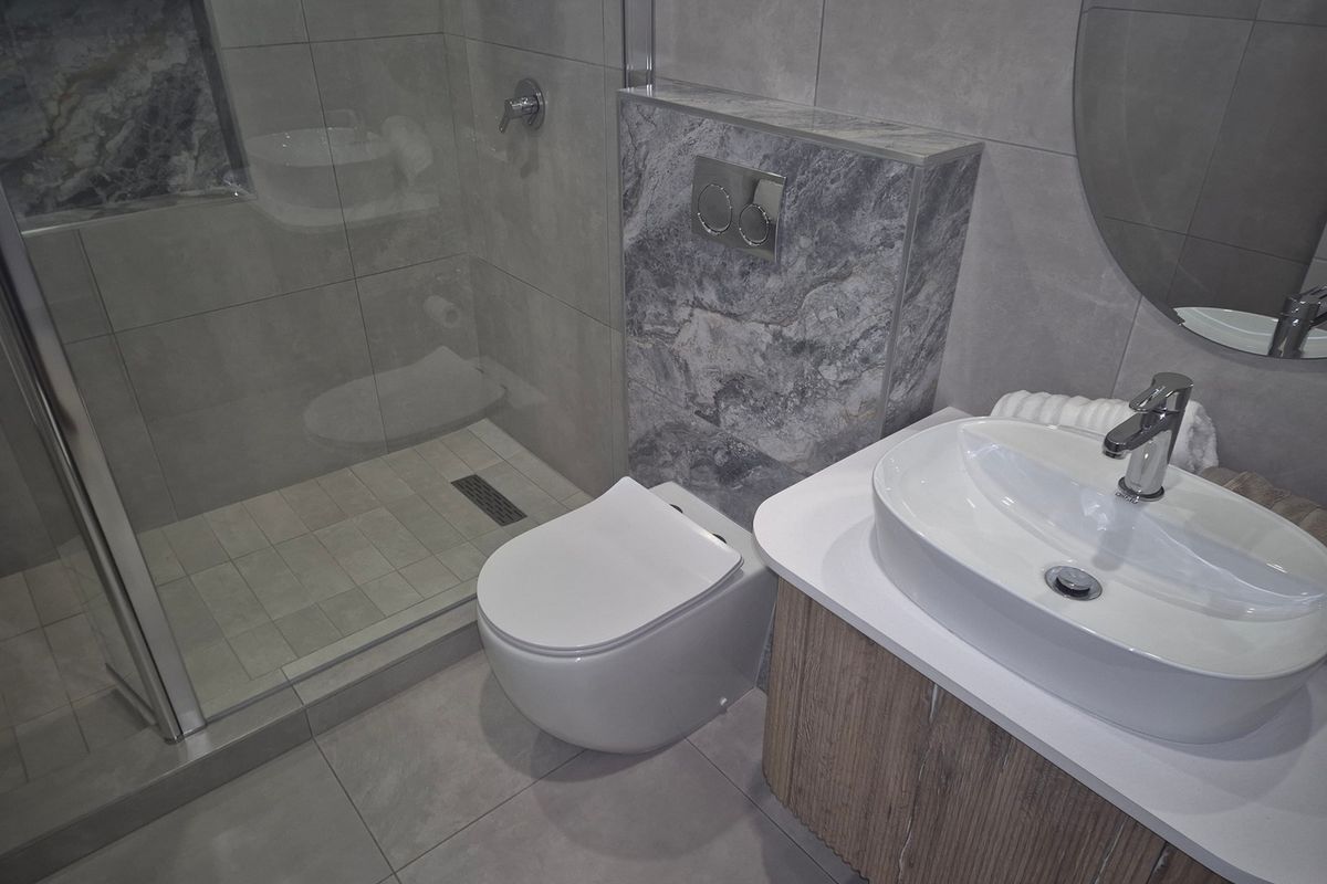 Modern bathroom featuring a walk-in shower with a recessed niche, wall-hung toilet, and a contemporary vanity with a vessel sink.