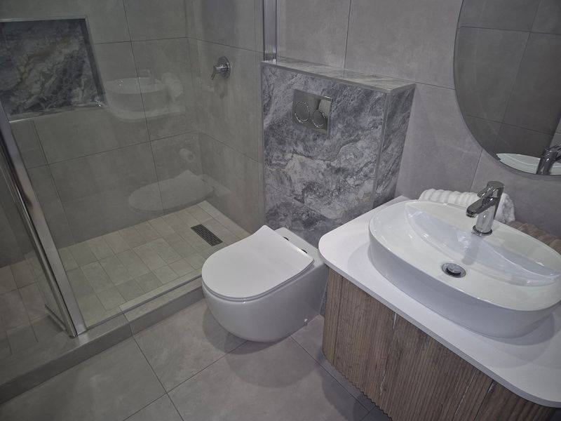 Modern bathroom featuring a walk-in shower with a recessed niche, wall-hung toilet, and a contemporary vanity with a vessel sink.