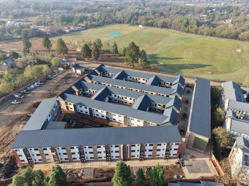 Aerial view of a multi-story apartment complex featuring pitched metal roofing, brick exterior finishes, and an internal courtyard layout under construction.
